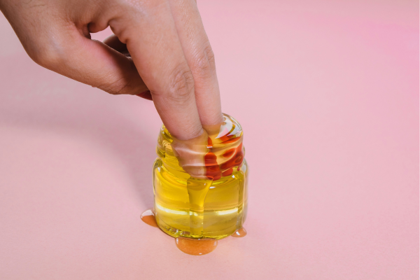 Tecnica del massaggio Tantra Yoni rappresentata da dita femminili che si bagnano dentro un vasetto di olio
