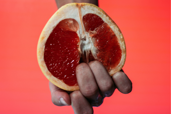 Immagine simbolica che rappresenta con buon gusto la pratica dello Yoni massage fai da te: una donna che tocca un frutto a forma di vulva