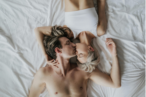 Coppia in intimità che si bacia nella posizione classica a letto