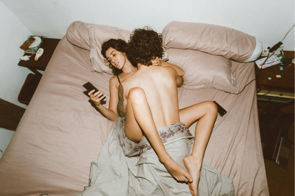 Coppia a letto nella posizione del missionario mentre lei è distratta dal cellulare