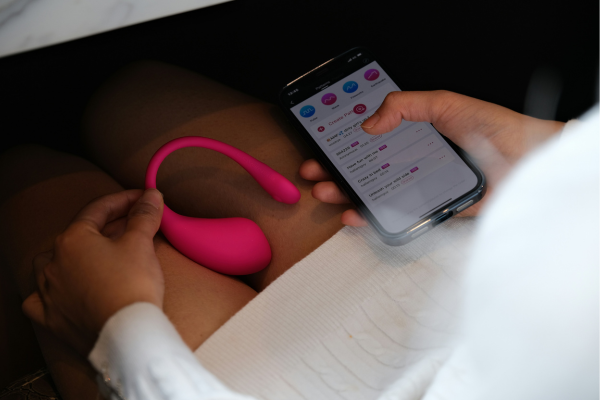 Lovense Lush in auto: come usare e nascondere un ovetto vibrante controllato da app Donna seduta in auto con ovetto vibrante Lovense Lush in mano, controllato da app sullo smartphone, esempio di sex toy discreto da portare e usare in macchina
