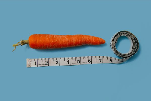 Consigli pratici per gestire un pene molto grande Carota con metro accanto per rappresentare i consigli pratici su come gestire un pene grande